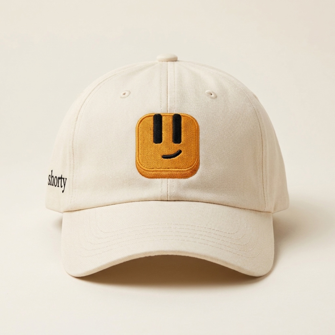 Cream baseball cap with an embroidered amber Shorty keycap patch